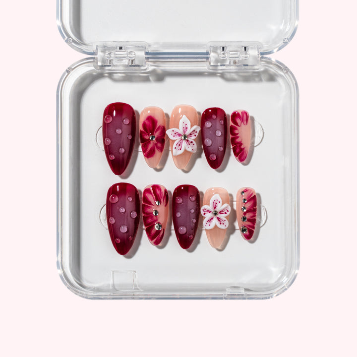 Amber Gentian nail set with burgundy base, 3D floral designs, rhinestones, and dew drops for a summer-inspired look.